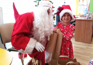 Oktawia pozuje do zdjęcia z Mikołajem i ze swoim prezentem.