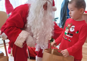 Maciuś pozuje do zdjęcia z Mikołajem i ze swoim prezentem.