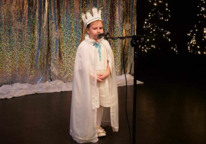 Hania w pelerynie królowej śniegu oraz koronie, prezentuje na scenie swój wierszyk.