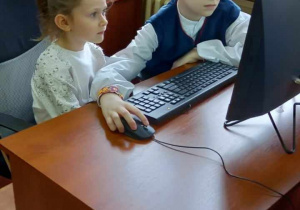 Przedszkolaki przy komputerze programują według instrukcji starszych kolegów.