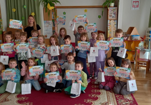 Wspólne zdjęcie przedszkolaków z Paniami Z Grupy Eventowej Sparta. Dzieci trzymają dyplomy i torby papierowe z upominkiem.
