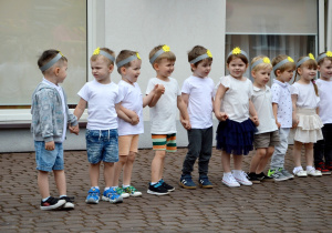 Maluszki w opaskach ze słoneczkiem podczas występu dla rodziców.