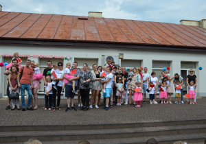 Pamiątkowe zdjęcie dzieci z grupy Promyczki z rodzicami na tarasie przedszkola. Z tyłu napis Mamo, Tato kocham Was.