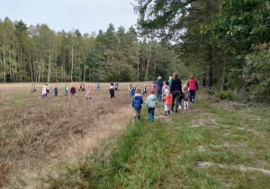 Spacer na leśnej ścieżce edukacyjnej z panią Leśnik. Pani Izabela wyjasnia dzieciom nowinki z życia lasu wczesną jesienią.