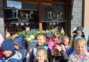 Motylki, 5-latki stoją przed witryną sklepu warzywnego Zielono Mi.