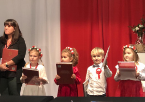 Nagrodzone dzieci stoja razem do wspólnego zdjęcia. Trzymają dyplomy i książeczki.
