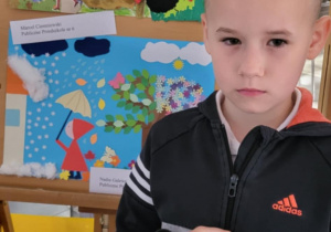 Marcel stoi przy swojej pracy plastycznej, która zdobyła II miejsce.