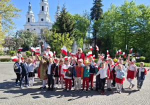 Dzieci w Parku 3 Maja pod pomnikiem upamietniającym Uchwalenie Konstytucji.