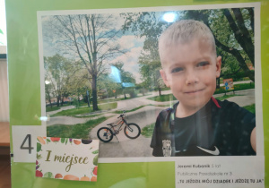 Chłopiec na tle miasteczka ruchu dla dzieci w oddali stoi rower.