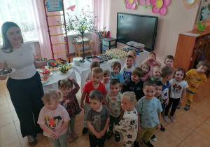 Maluszki i pani Kasia przy stole z owocowymi przekąskami.