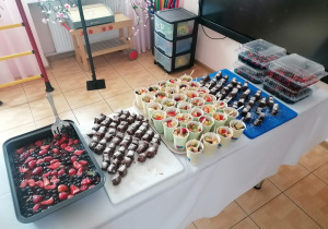 Na stole umieszczono; galaretkę owocową, ciasto marchewkowe i sałatkę owocową w kubeczkach.
