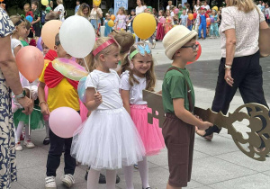 Kolorowy korowód dzieci, chłopiec w kapeluszu słomkowym trzyma duży Klucz do Miasta.