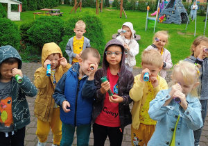 Przedszkolaki patrzą w mozaikowe lornetki.