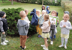 Chłopiec trzyma niebieski worek ze skarbem. Obok niego stoją dzieci.