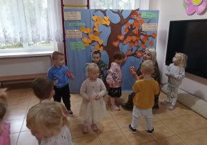 Pani Ewa przypina z Jagódkami serduszka z ich imionami na Drzewie Przyjaźni.