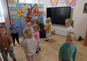 Pani Ewa przypina z Jagódkami serduszka z ich imionami na Drzewie Przyjaźni.