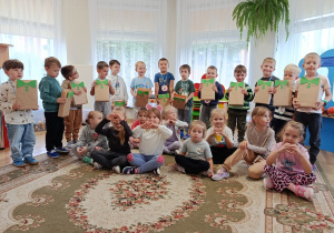 Wspólne zdjęcie Słoneczek. Dziewczynki siedzą przed chłopcami, którzy trzymają prezenty, a na szyi mają medal z napisem Super Chłopak.