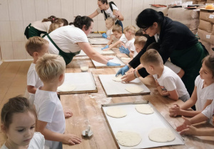 Promyczki przygotowują pizzę.