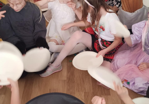 Zabawa z talerzykami służącymi jako wachlarze do rozdmuchiwania kolorowej, pociętej drobno bibuły.