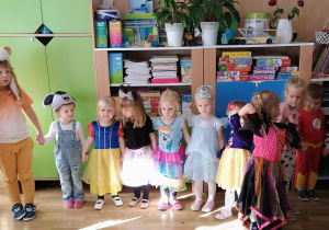 Dzieci w kolorowych, bajkowych przebraniach tańczą w kole.