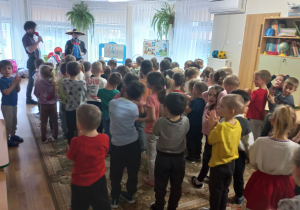 Dzieci stoją na dywanie podczas koncertu. Przed nimi mężczyzna w sombrero i meksykańskim stroju.