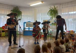 Muzyk z Meksyku obok stoi dwoje dzieci w sombrero.