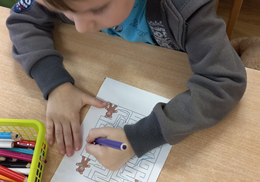 Chłopiec rysuje drogę misia do klocków w labiryncie.