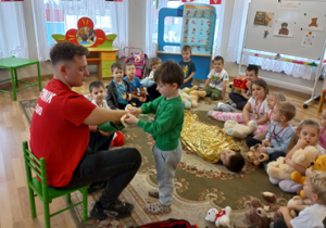 Chłopiec bandażuje przedramię ratownika.