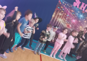 Dzieci ustawione w półkolu tańczą.