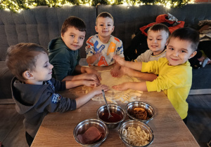 Chłopcy formują placek pizzy.