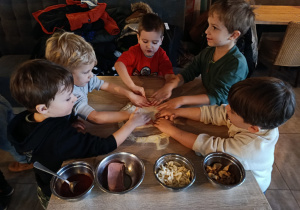 Chłopcy formują placek pizzy.
