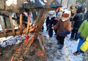 Dzieci dokładają smakołyki do paśnika.