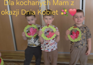 Trzej chłopcy z grupy Jagódki trzymają w rączkach laurki dla swoich mam.