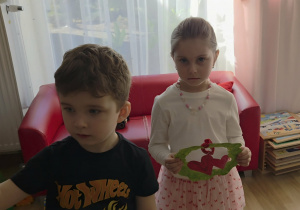 Dziewczynka i chłopiec stoją z laurkami.