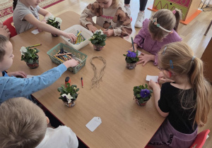 Sadzenie bratków przy stoliczkach pod nadzorem prowadzących warsztaty.