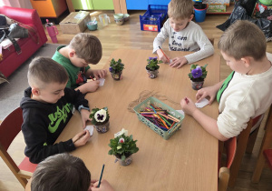 Sadzenie bratków przy stoliczkach pod nadzorem prowadzących warsztaty.