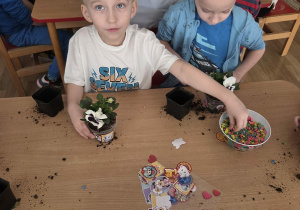 Sadzenie bratków przy stoliczkach pod nadzorem prowadzących warsztaty.