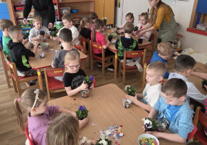Sadzenie bratków przy stoliczkach pod nadzorem prowadzących warsztaty.