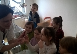 pani stomatolog pokazuje dzieciom dentystyczne akcesoria