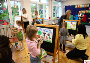Pola przy sztaludze maluje swoja prace konkursową.
